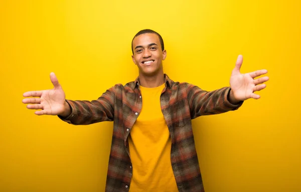 Junger Afrikanisch Amerikanischer Mann Auf Leuchtend Gelbem Hintergrund Präsentiert Und — Stockfoto