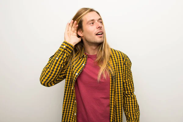 Sarışın adam uzun saçlı ve kareli gömlek için bir şey kulak el koyarak dinleme