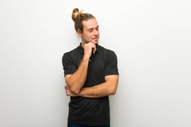 Beyaz duvar tarafına el ile çeneme seyir üzerinde uzun saçlı sarışın adam