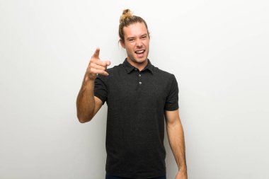 Beyaz duvar kötü bir durum ve önüne göstererek sinirli üzerinde uzun saçlı sarışın adam