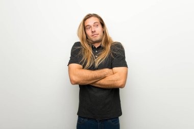 Beyaz duvar yapım şüpheler jest omuz kaldırma sırasında üzerinde uzun saçlı sarışın adam