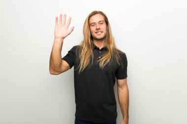 Beyaz duvar mutlu ifade ile el ile selamlayan üzerinde uzun saçlı sarışın adam