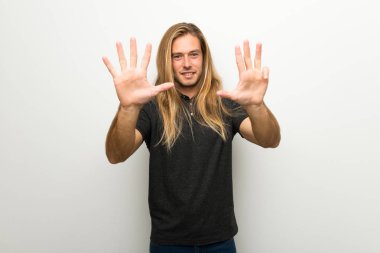 Beyaz duvar dokuz parmaklı sayma üzerinde uzun saçlı sarışın adam