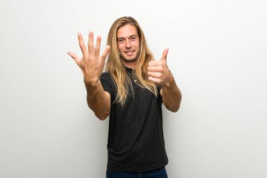 Beyaz duvar altı parmak ile sayma üzerinde uzun saçlı sarışın adam