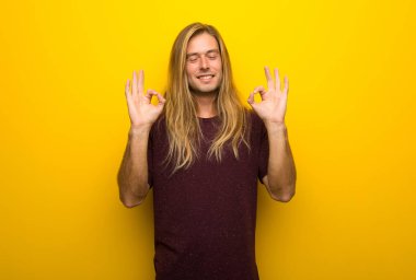 Zen sarı duvarın üzerinden uzun saçlı sarışın adam poz