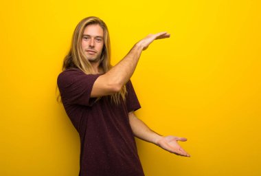 Sarı duvarın boşaltmak holding üzerinden uzun saçlı sarışın adam bir reklam eklemek için