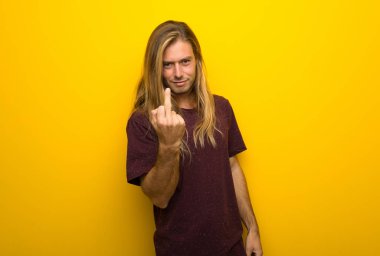 Boynuz jest yaparak sarı duvarın üzerinden uzun saçlı sarışın adam