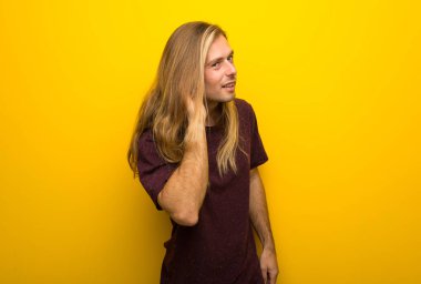 Bir şey kulak el koyarak dinleme sarı duvarın üzerinden uzun saçlı sarışın adam