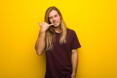 Telefon jest yaparak sarı duvarın üzerinden uzun saçlı sarışın adam. Bana arka işareti de