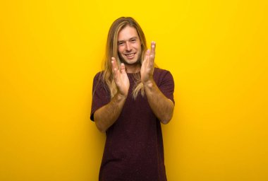 Bir konferansta sunum sonrası sarı duvar alkış üzerinde uzun saçlı sarışın adam