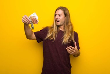 Bir sürü para alarak sarı duvarın üzerinden uzun saçlı sarışın adam