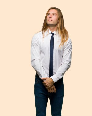 İzole arka plan üzerinde ciddi bir yüz ile bakarken uzun saçlı sarışın iş adamı