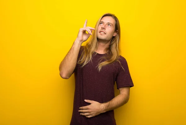 Hombre Rubio Con Pelo Largo Sobre Pared Amarilla Señalando Una — Foto de Stock