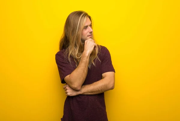 Hombre Rubio Con Pelo Largo Sobre Pared Amarilla Mirando Lado — Foto de Stock