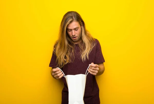 Blond Man Long Hair Yellow Wall Surprised While Holding Lot — Stock Photo, Image