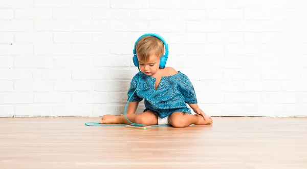 Bedårande Liten Baby Lyssnar Musik Vitt Tegel Bakgrund — Stockfoto