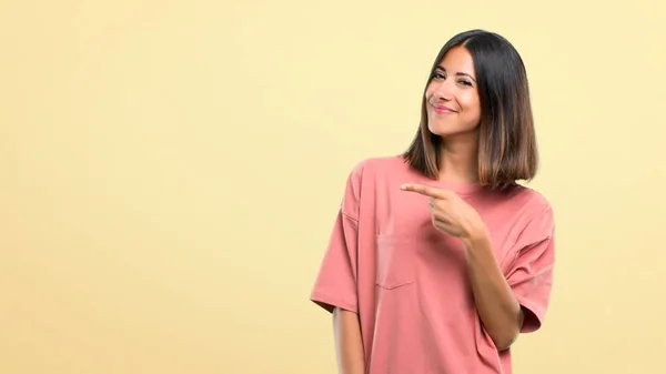 ピンクのシャツ側に指を指すと 黄色の背景に製品を提示を持つ少女 — ストック写真