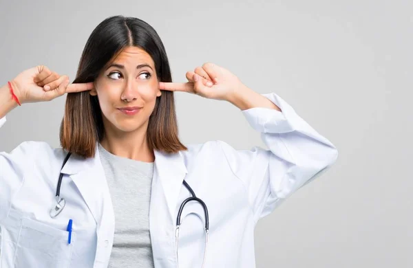 Doctor Woman Stethoscope Covering Both Ears Hands Grey Background — Stock Photo, Image