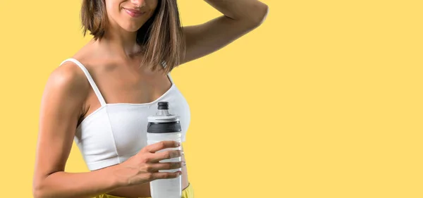 黄色の背景にボトルを持つスポーツ女性 — ストック写真