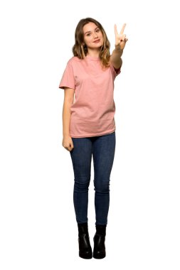A full-length shot of a Teenager girl with pink sweater showing thumb down sign with negative expression on isolated white background