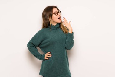 Genç kız esneme ve el ile geniş açık ağız kapsayan beyaz duvar üzerinde