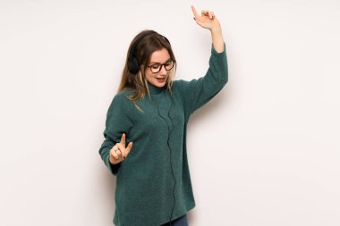 Genç kız kulaklık ile müzik ve dans beyaz duvar üzerinde