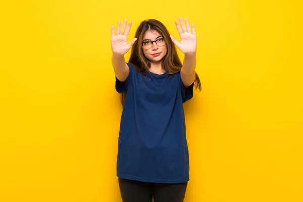 Mujer Joven Con Gafas Sobre Pared Amarilla Haciendo Gesto Parada —  Fotos de Stock