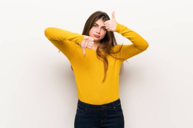 İyi-kötü işaret yapma sarı kazaklı genç kadın. Arasında kararsız Evet ya da değil