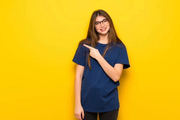 Mujer Joven Con Gafas Sobre Pared Amarilla Apuntando Hacia Lado — Foto de Stock