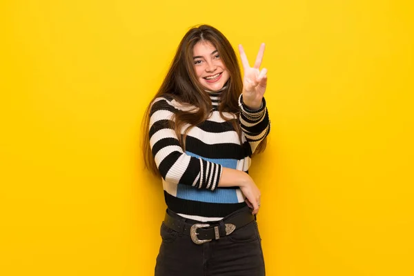 Молода Жінка Над Жовтою Стіною Посміхається Показує Знак Перемоги — стокове фото