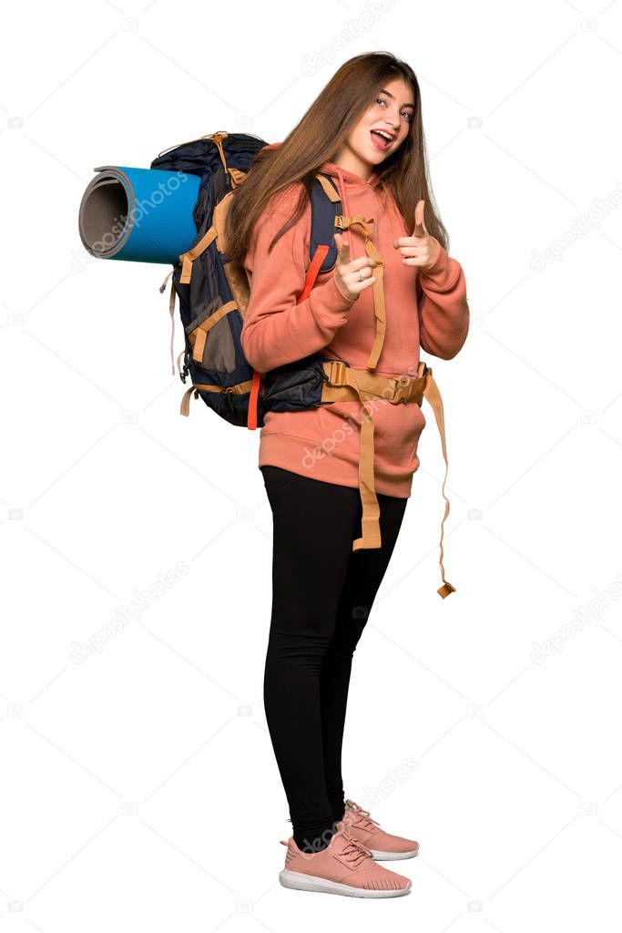 Full-length shot of Hiker girl pointing to the front and smiling on isolated white background