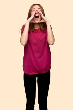 Bağırarak ve izole sarı zemin üzerine bir şey ilan genç Kızıl saçlı kız