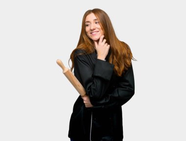Young redhead chef woman looking to the side with the hand on the chin on isolated grey background