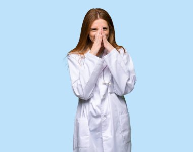 Kızıl saçlı doktor kadın çok izole mavi arka plan dudaklarından kapsayan süre gülümseyen