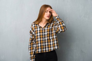 Genç Kızıl saçlı kız yorgun ve hasta ifade ile grunge duvarın üzerinden