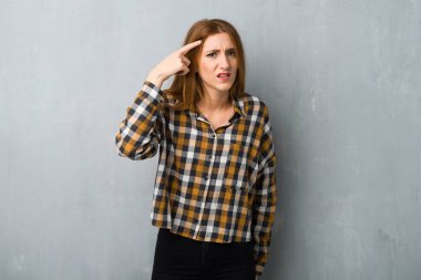 Genç kızıl saçlı kız grunge duvarını aştı. Çılgınlık hareketi yapıyor. Parmağını kafanın üstüne koyuyor.