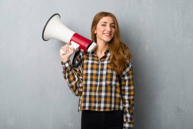 Grunge duvar bir megafon tutan genç Kızıl saçlı kız