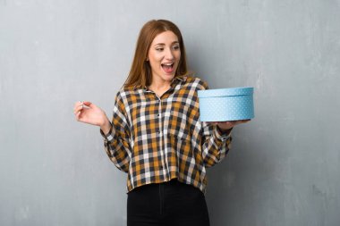 Hediye kutusu elinde tutan grunge duvarın üzerinden genç Kızıl saçlı kız