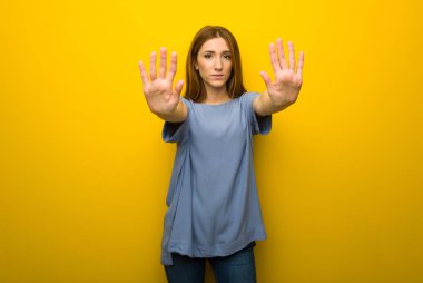 Genç Kızıl saçlı kız Dur jest yapmak için sarı duvar arka plan üzerinde bir görüş ile hayal kırıklığına