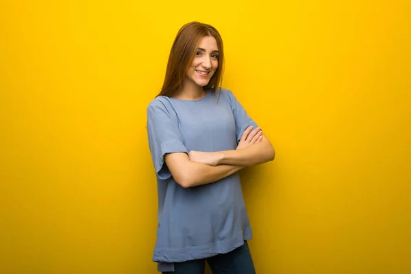 正面位置で交差腕を維持する黄色の壁の背景の上の若い赤毛の女の子 — ストック写真