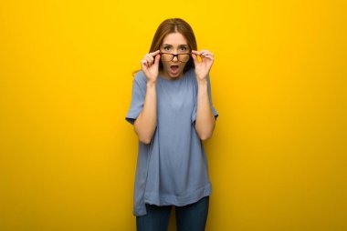 Sarı duvar arka plan ile gözlük ve sürpriz genç Kızıl saçlı kız