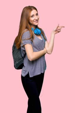 Kızıl saçlı öğrenci kadın işaret eden parmağa yan yan pozisyonda izole pembe arka plan