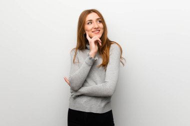 Kızıl saçlı kız beyaz duvar ararken bir fikir düşünce üzerinde