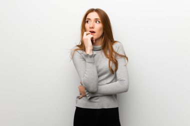 Kızıl saçlı kız beyaz duvar ararken şüpheleri üzerinde