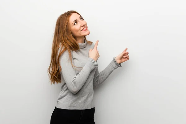 Roodharige Meisje Witte Muur Aan Wijzen Met Wijsvinger Opzoeken — Stockfoto