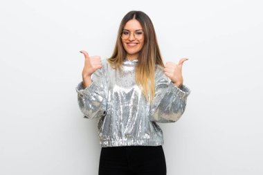 Her iki el ile jest Yaşasın vererek ve gülümseyen beyaz duvarın üzerinden gözlüklü genç kadın