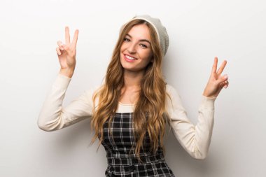 Zarif şekilde gülümseyen şapka giyen kadın ve gösteren zafer her iki el ile oturum açmak