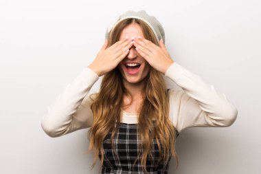 Zarif şekilde gözler eller tarafından kapsayan şapka giyen kadın. İleride ne olduğunu görmek için sürpriz