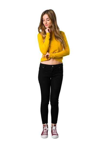 分離の白い背景の上のあごに手を見下ろし黄色のセーターと若い女の子のフルレングス ショット — ストック写真