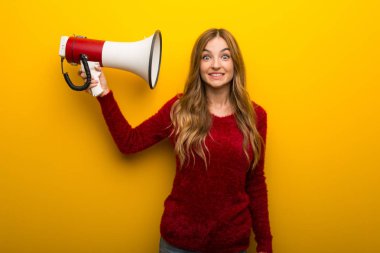 Çok gürültü yapar bir megafon alarak canlı sarı zemin üzerine genç kız